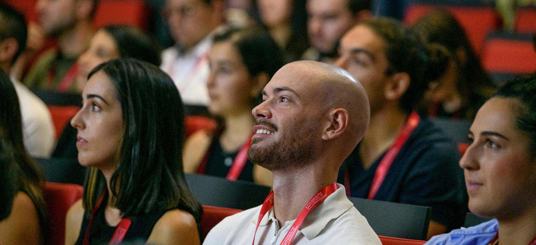 Students seated in a conference auditorium, attentively listening to a speaker during a welcome event